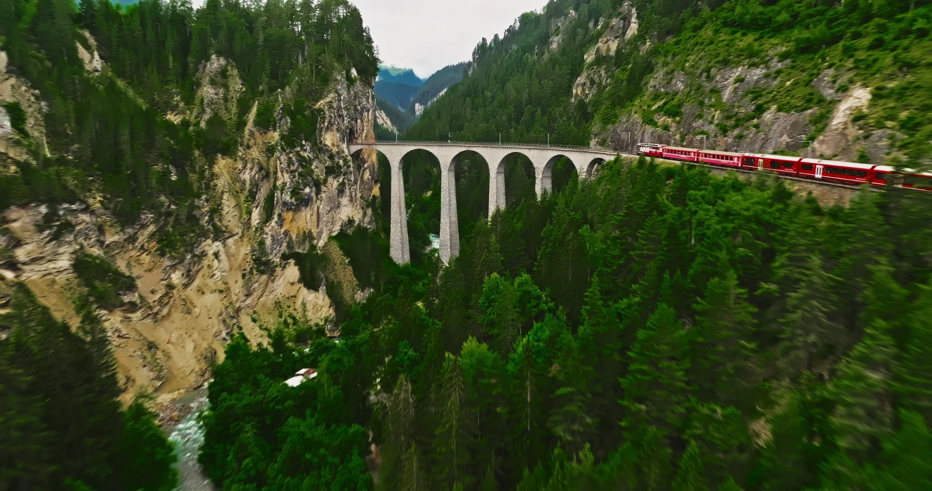 Red train crossing the Landwasser Viaduct in the Swiss Alps