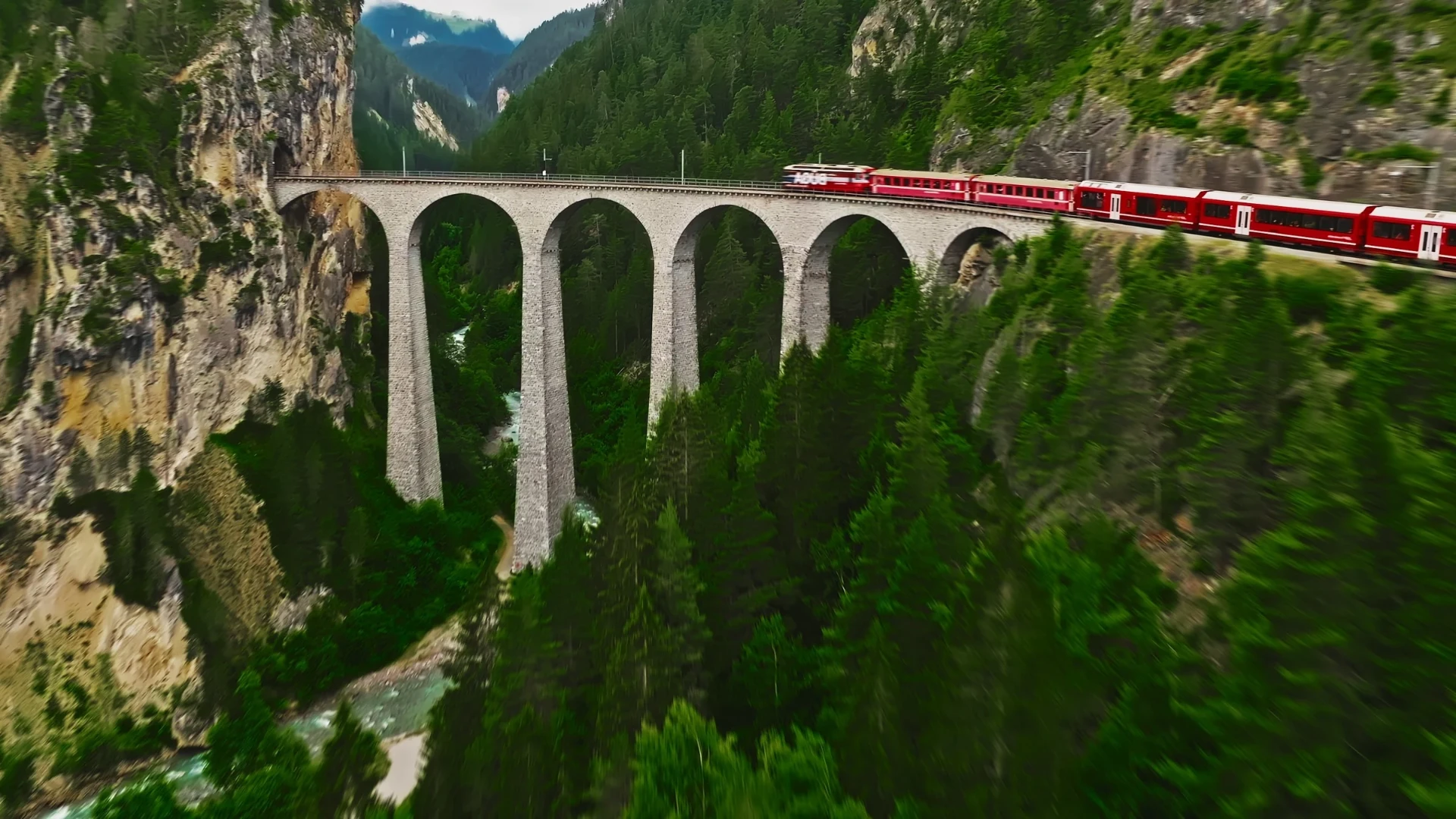 Red train crossing the Landwasser Viaduct above a forested gorge in Switzerland