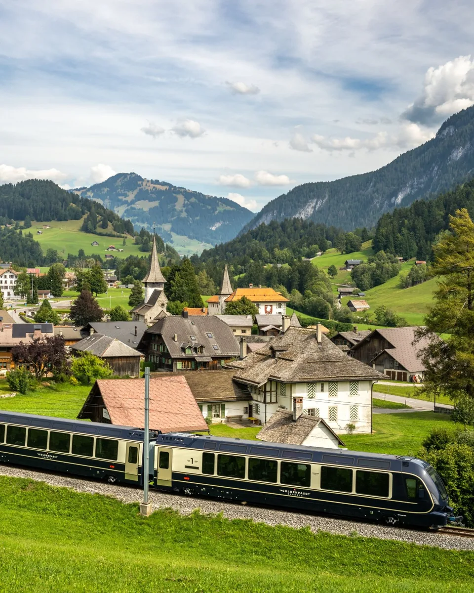 GoldenPass Express panoramic train passing the village of Rougemont in the Swiss Alps