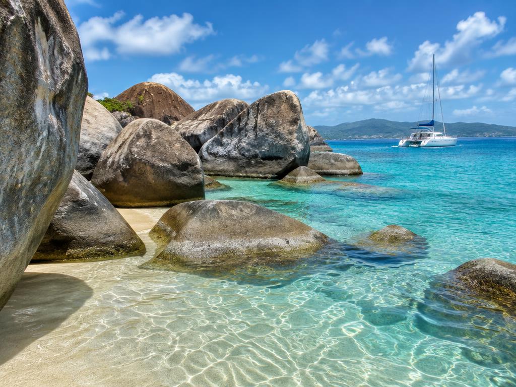 Catamaran moored beside rounded granite rocks